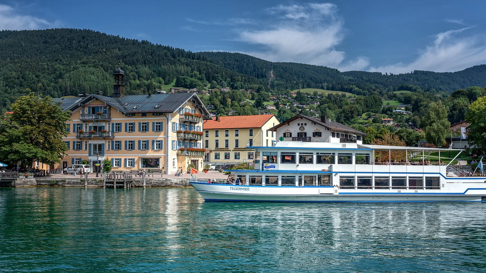 Passenger boat by the Tegernsee waterfront and buildings.
