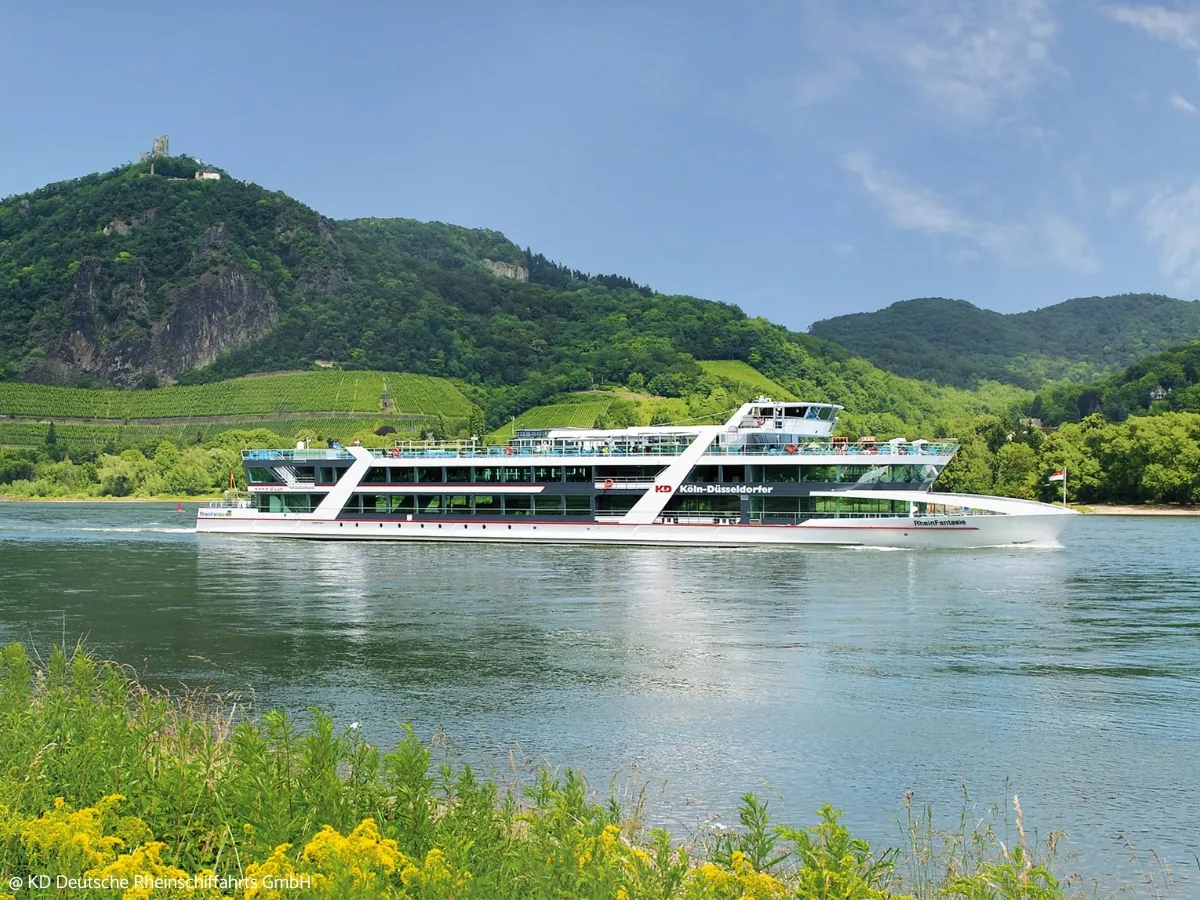 Passenger boat on a river below green hills.